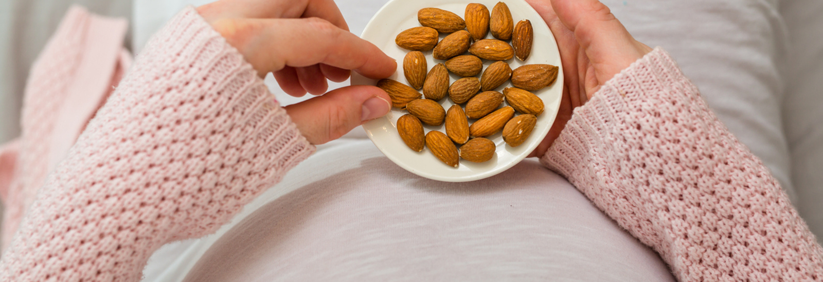 Afbeelding van zwangere vrouw eet amandelen